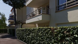 Un edificio residencial de varios pisos con balcones, un camino de entrada pavimentado y un seto bien cuidado.