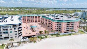 Un hotel de varios pisos con piscina en la azotea, estacionamiento y vistas del paisaje circundante.
