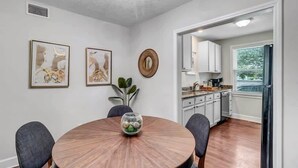 A dining area with a round wooden table, four chairs, and two framed artworks on the wall. - Modern 2 BR Condo - 2 block from San Marco (Jacksonville)