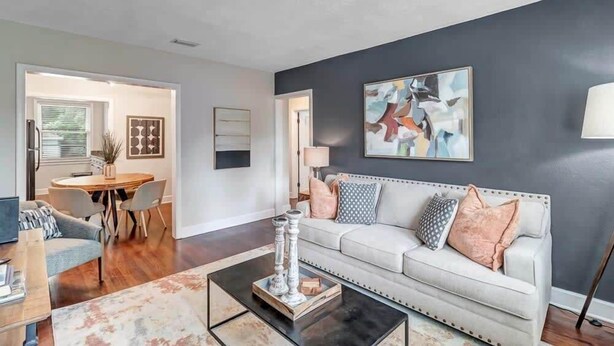 A living room with a white sofa, a coffee table, and a painting on the wall.