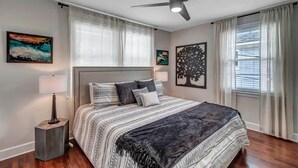 A bedroom with a bed, a ceiling fan, and artwork on the walls.