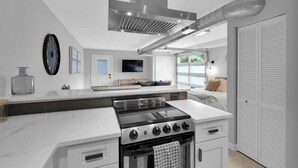 A modern kitchen with a central island, built-in oven, and a large window. - Chic & modern studio in the heart of San Marco! (Jacksonville)