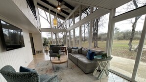 A spacious living room with a large window, a sofa, a chair, and a coffee table.