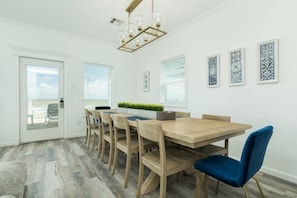 Un espace repas avec une table et des chaises en bois, un lustre et des œuvres d’art murales à motifs.