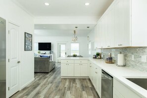 Une cuisine moderne avec des meubles blancs, un îlot central et un revêtement mural composé de carreaux de couleur claire.