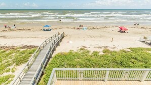 A beach with a wooden walkway, beach umbrellas, and a few people. - Stunning Ver La Mer - Direct Ocean & Beach Access! (Surfside Beach)