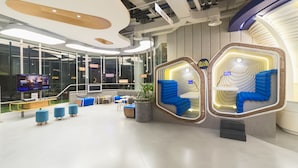 Interior moderno com uma ampla parede de vidro, assentos azuis e uma televisão.