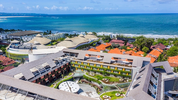 Um resort com piscina, vista para a praia e um edifício grande com design circular.