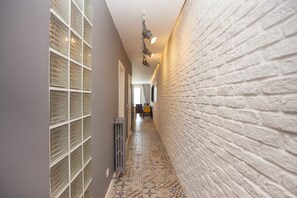 A narrow hallway with a tiled floor, a white brick wall, and a radiator. - Modern 3BR · Bosphorus View · Central (Istanbul)