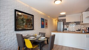 A modern kitchen with white cabinets, a dining table with chairs, and a framed map on the wall.