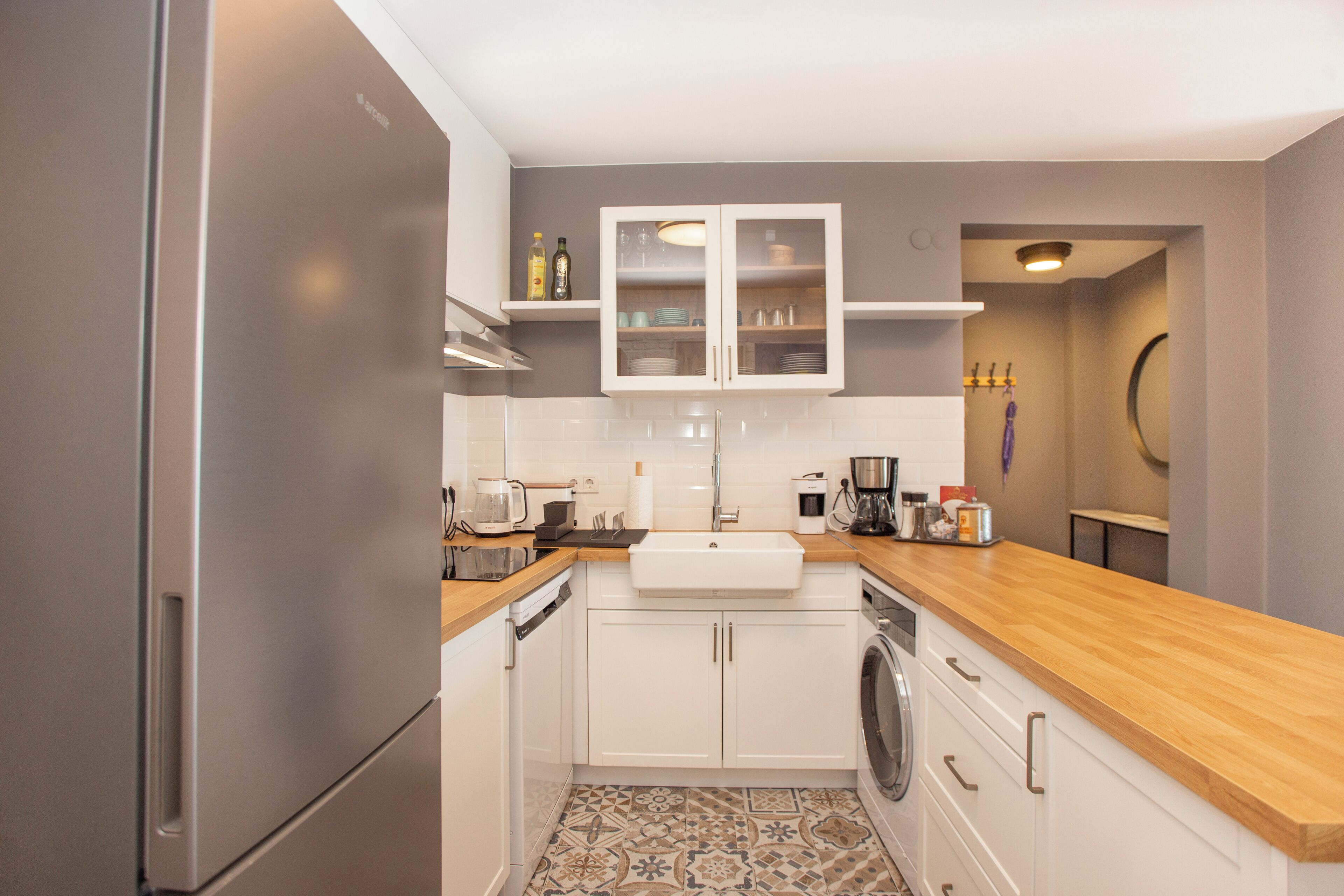 A modern kitchen with stainless steel appliances, white cabinetry, and a wooden countertop.
