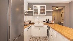 Une cuisine moderne dotée d’appareils électroménagers en acier inoxydable, de meubles de rangement blancs et d’un plan de travail en bois.