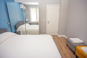A bedroom with a bed, a bedside table, a mirror, a wardrobe, a door, and a small bench with towels. - Modern 3BR · Bosphorus View · Central (Istanbul)