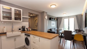 A modern kitchen with a built-in washing machine, a wooden countertop, and a dining area with a table and chairs.
