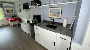 A compact kitchen with a sink, microwave, and white cabinets. - Port Williams Room -KingBed, Patio, Downtown (Wolfville)