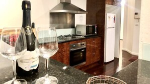 Een moderne keuken met een gasfornuis, magnetron, oven en een roestvrijstalen afzuigkap.