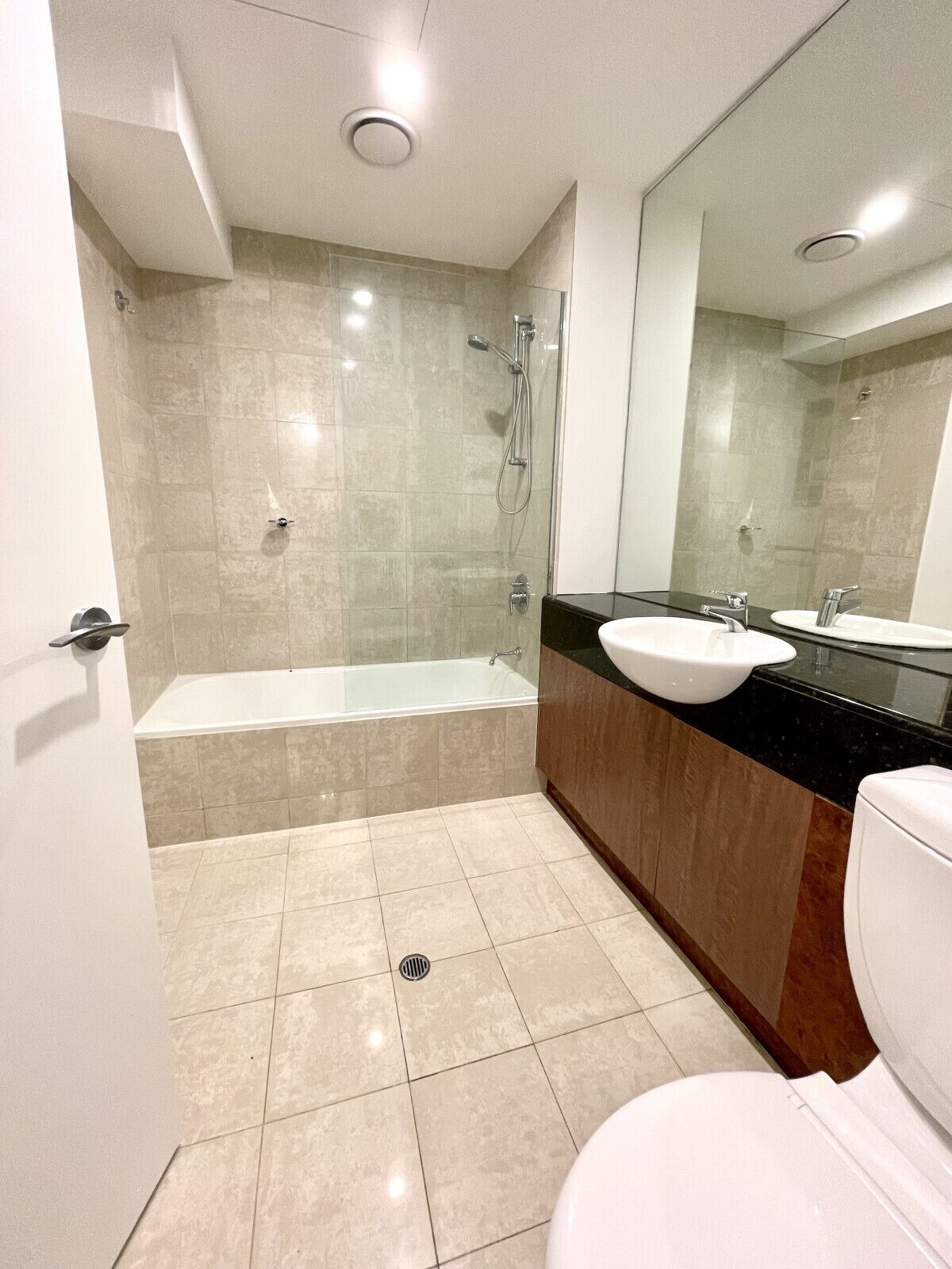 A modern bathroom with a glass-enclosed shower, a bathtub, a sink, and a toilet.