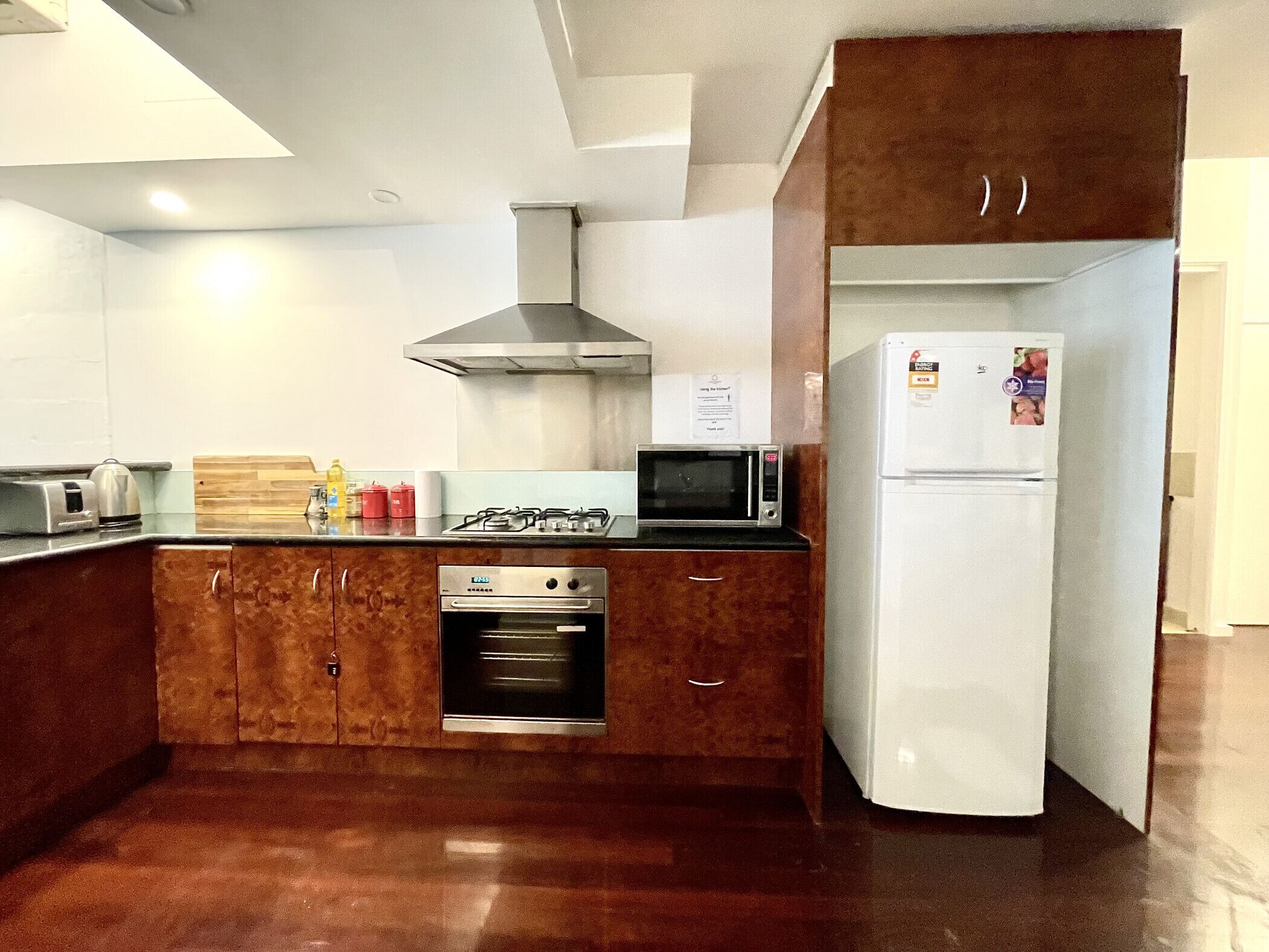 A modern kitchen with a gas stove, microwave, oven, and a white refrigerator.