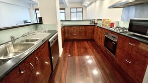 Een moderne keuken met houten kastjes, roestvrijstalen apparatuur en een zwart aanrecht.