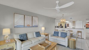 Un salon moderne avec deux canapés, une table basse et un ventilateur de plafond.