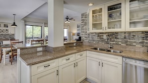 A modern kitchen with granite countertops, white cabinetry, and a backsplash with mosaic tiles. - Pet Friendly! Modern 2 Bedroom/2 Bathroom Condo in Shelter Cove Marina (Hilton Head Island)
