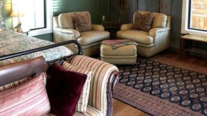 Ein Zimmer mit zwei beigen Sesseln, einem gemusterten Sofa und einem Teppich mit Muster.