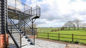Una escalera que lleva a un edificio con vista a un campo verde y una valla de madera.
