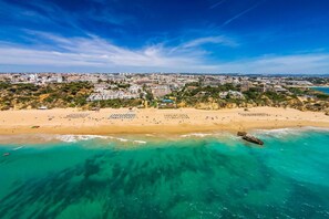 Di pantai, pasir putih, kursi berjemur, dan payung pantai