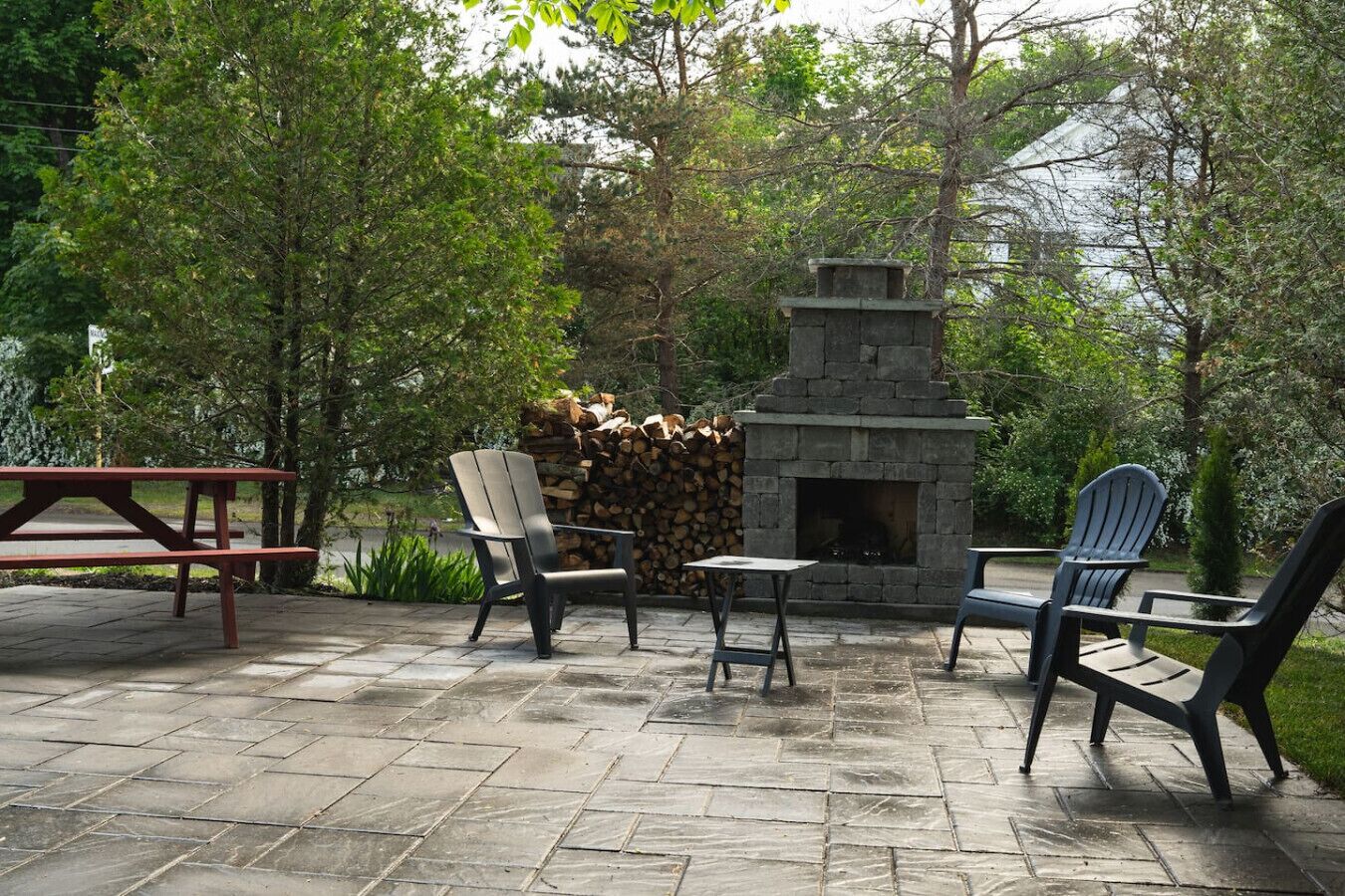 An outdoor patio with a stone fireplace, seating, and a picnic table.