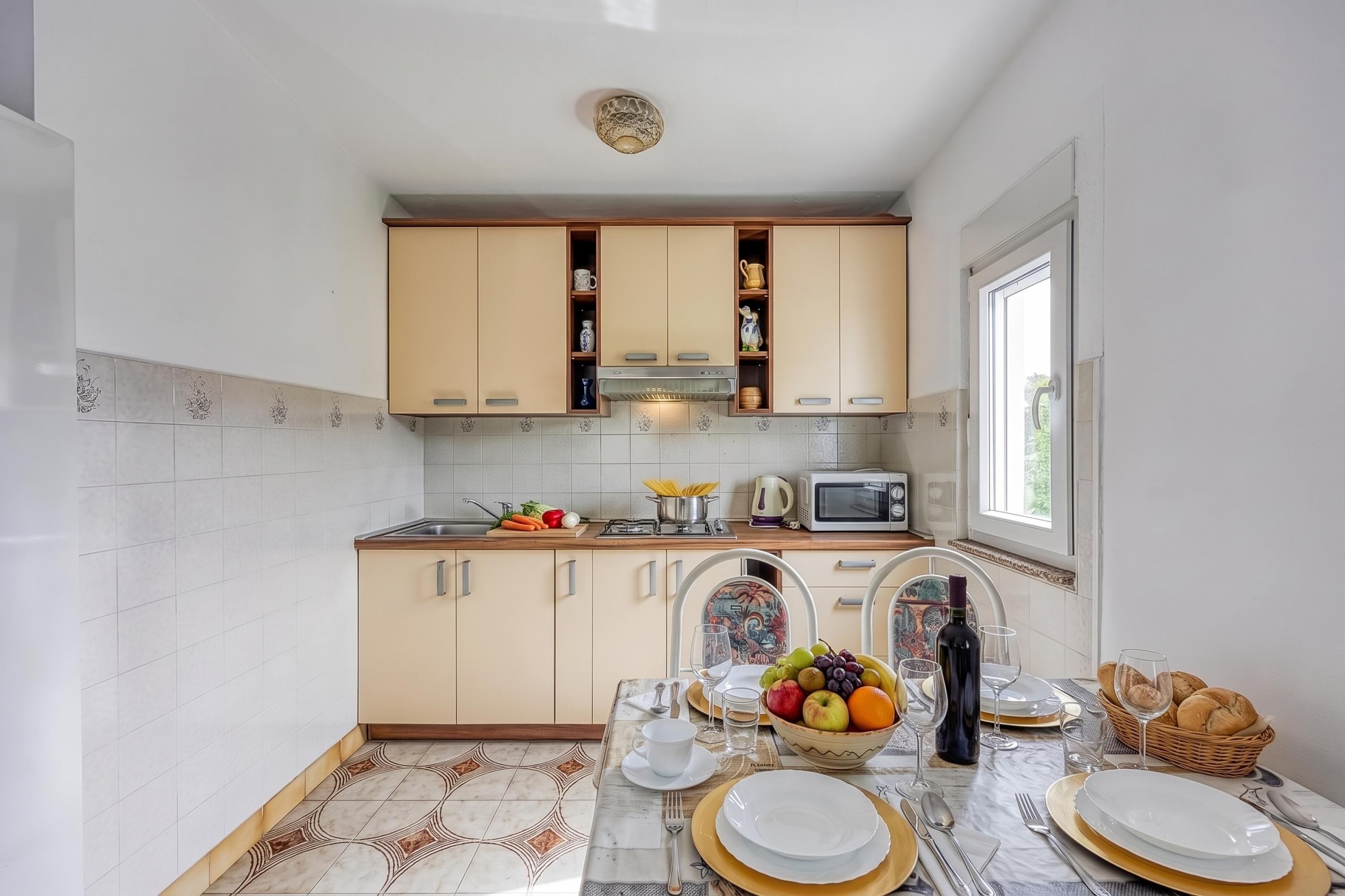 A modern kitchen with white cabinets, a microwave, and a dining area set for a meal.