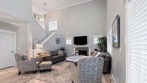 A living room with a sofa, armchairs, a TV, and a fireplace. - CDA retreat near Sanders Beach with hot tub (Coeur d'Alene)