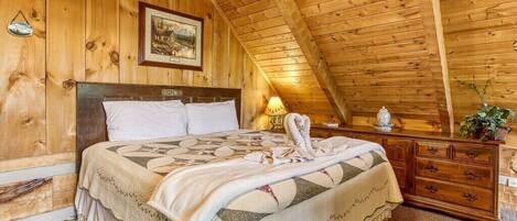 A cozy wooden room with a bed, a nightstand, and a dresser.
