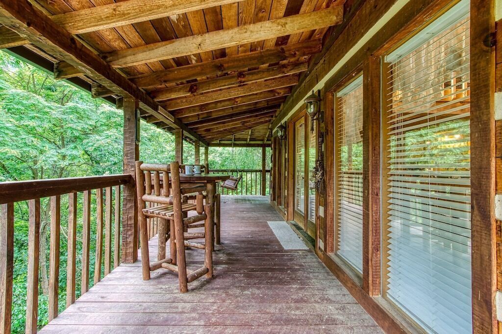 Eine Holzterrasse mit Tisch und Stühlen, umgeben von Glasfenstern und einem Hollerleger.