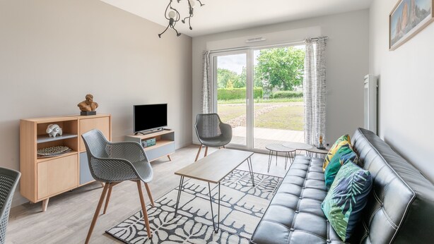 A modern living room with a sofa, chairs, a TV, and a wooden cabinet.