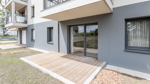 A modern building with a flat roof, large windows, and a wooden deck area.
