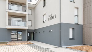 A modern building with a grey and white facade, a visible entrance, and a nameplate reading "CASA MADERA".