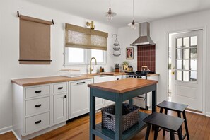 Una cocina moderna con armarios blancos, encimera de madera, una isla central y una estufa.