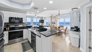 Una cocina moderna con una isla central, un comedor con vistas y un amplio ventanal con vistas al océano.