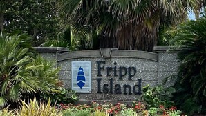 A sign for Fripp Island with a logo, surrounded by tropical plants and flowers. - 338 Capt John Fripp Villa W/Cart, Cards Available! (Fripp Island)