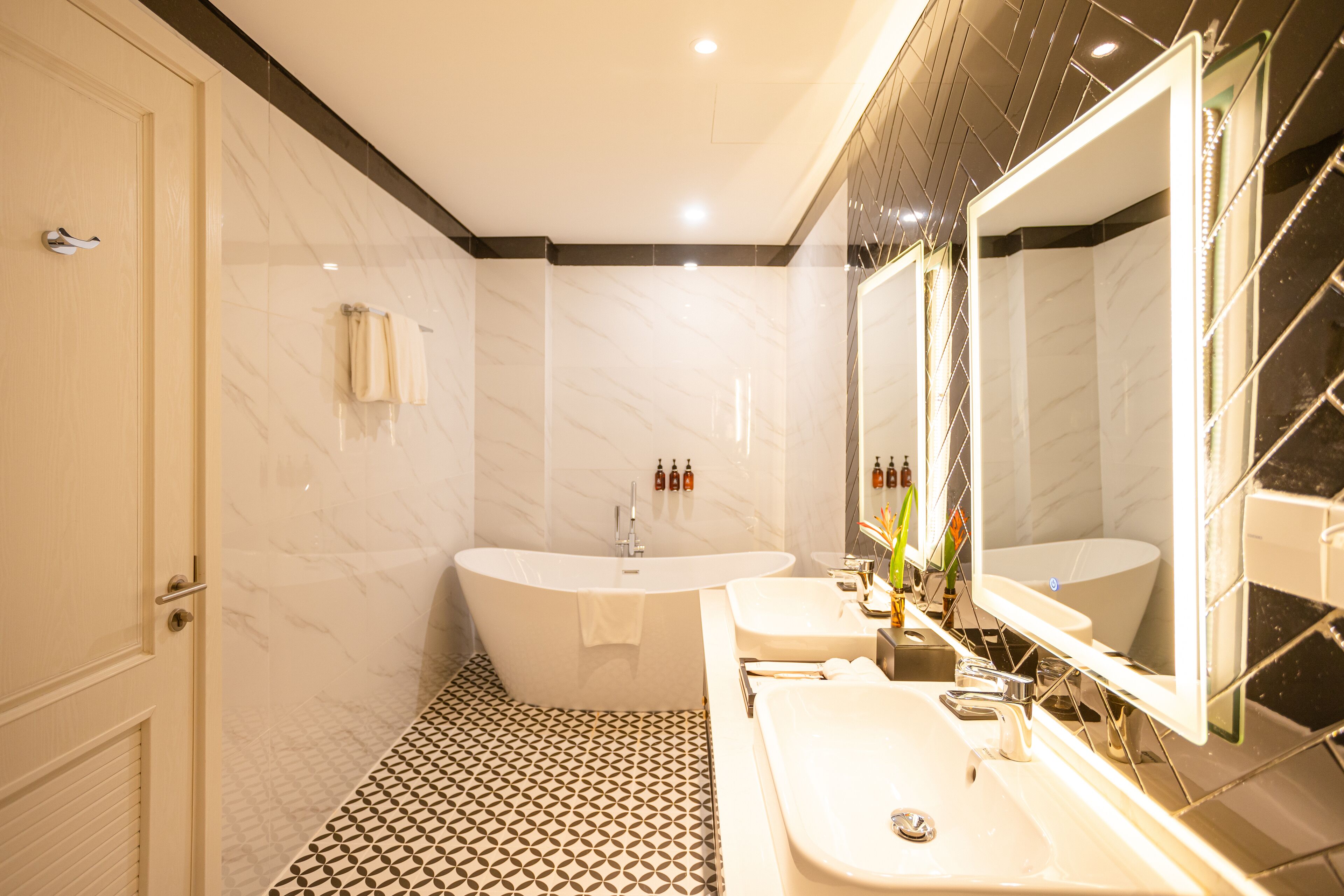 A modern bathroom with a freestanding bathtub, two sinks, and a large mirror.