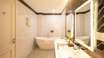 A modern bathroom with a freestanding bathtub, two sinks, and a large mirror.