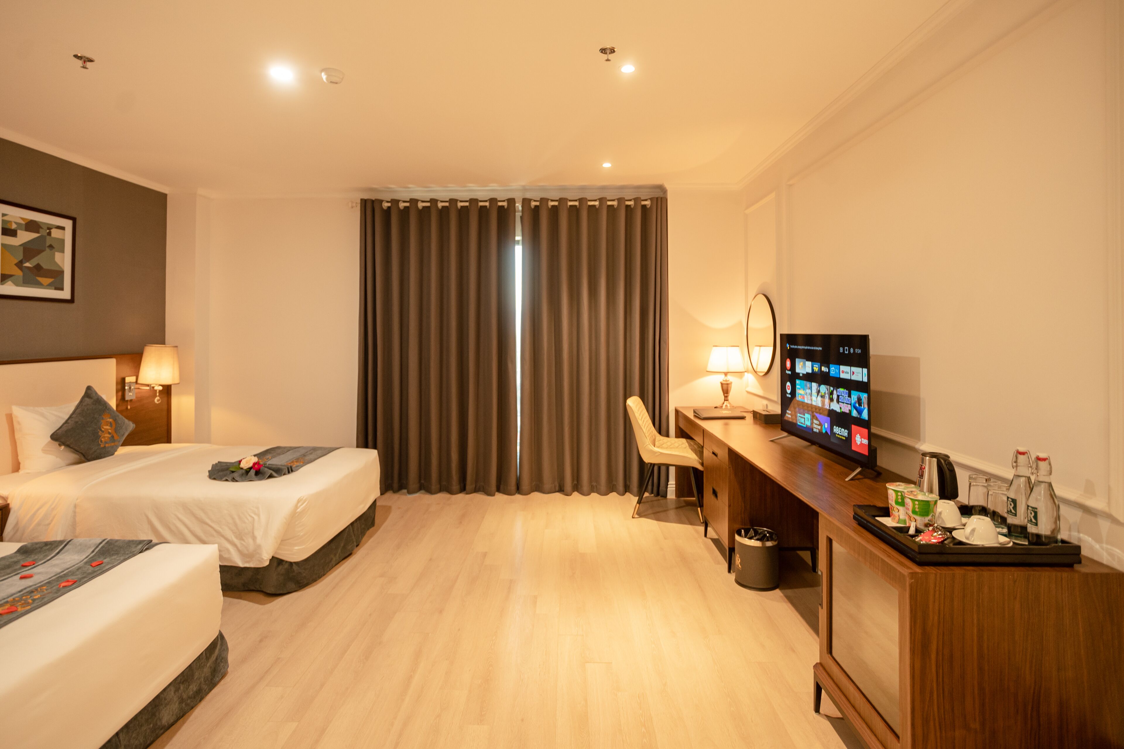 Habitación de hotel con dos camas, un escritorio, un televisor y un minibar.
