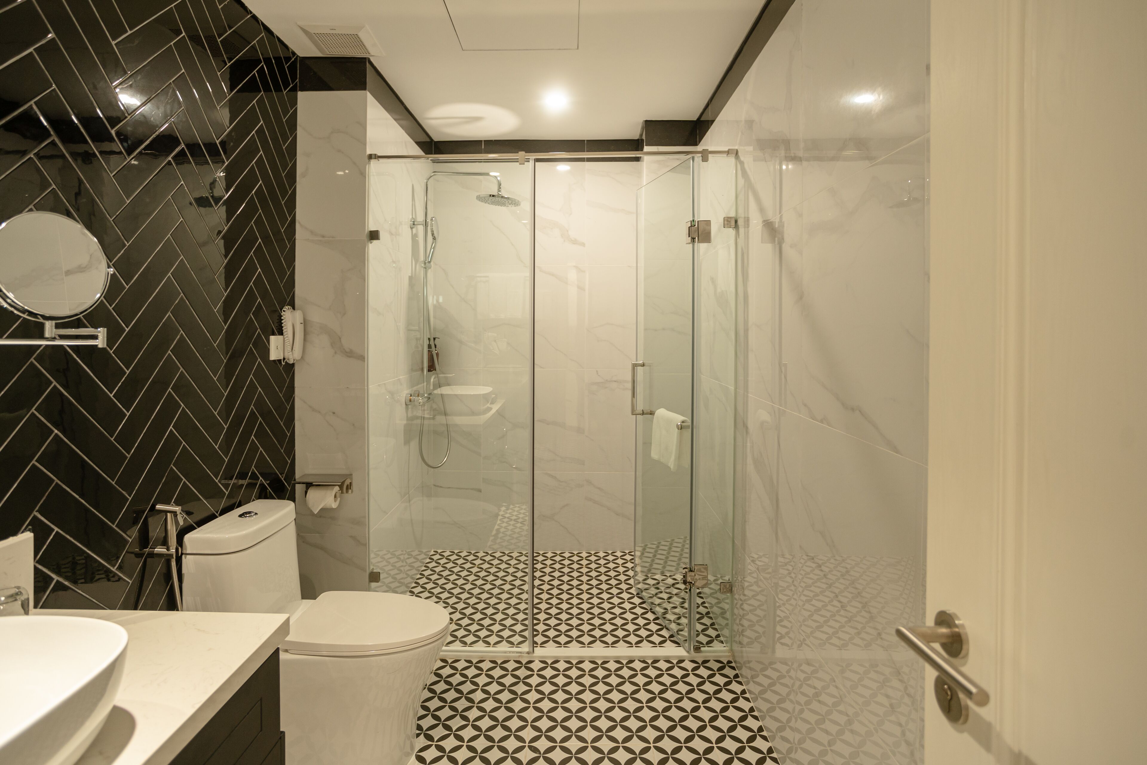 A modern bathroom with a glass-enclosed shower, a toilet, and a sink.