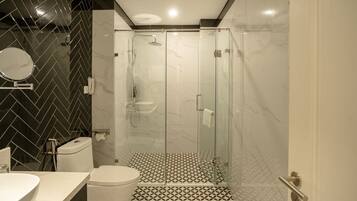 A modern bathroom with a glass-enclosed shower, a toilet, and a sink.