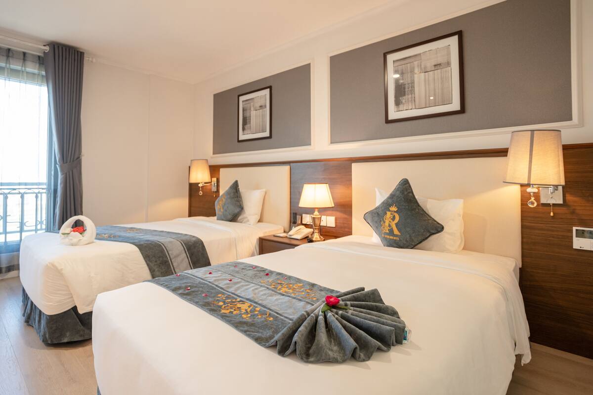 Een hotelkamer met twee bedden, een balkon en uitzicht op de stad.