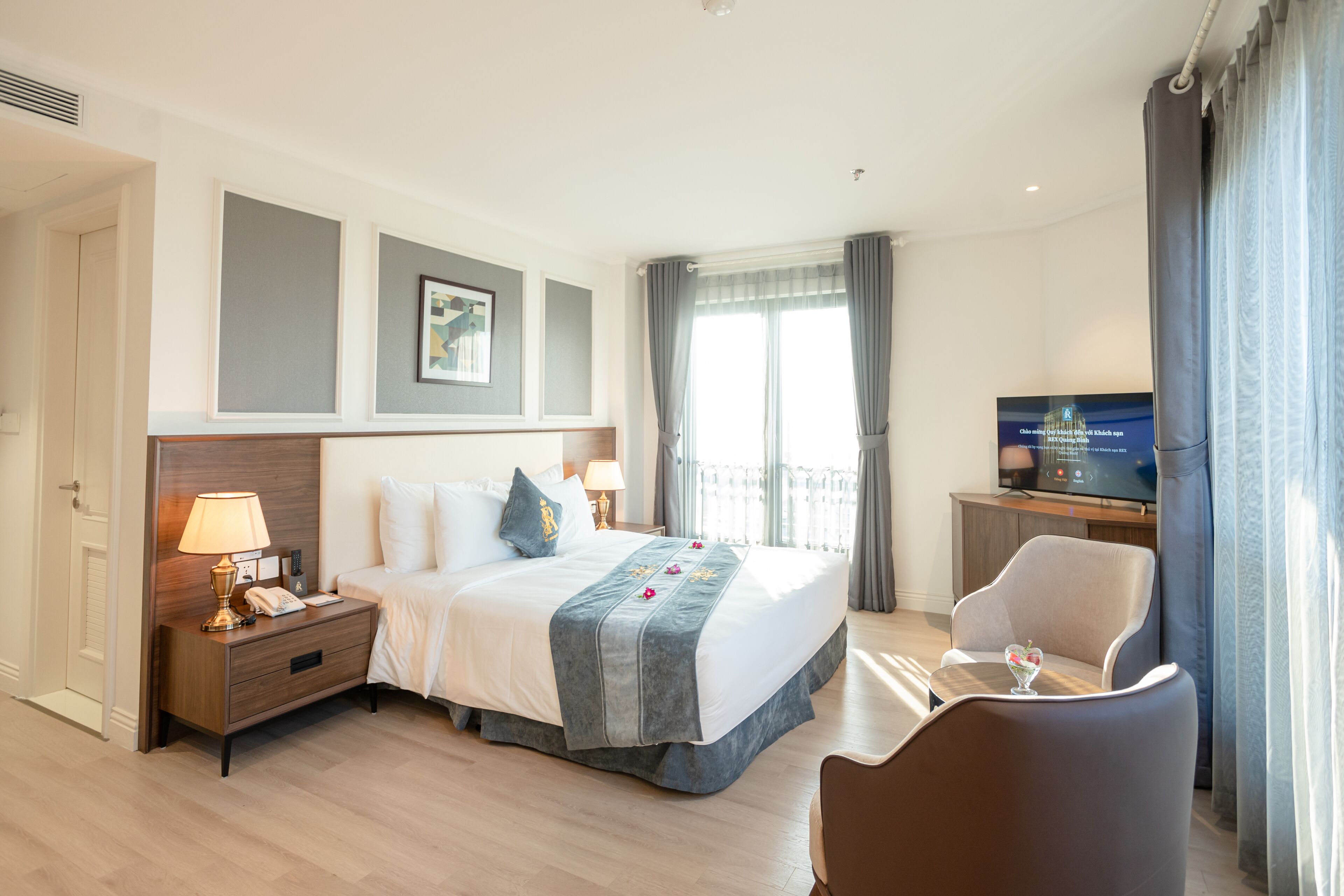 A hotel room with a bed, bedside table, lamp, TV, and a chair.