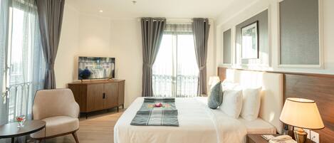 Une chambre d’hôtel avec un grand lit, un bureau avec une lampe, une chaise, une télévision et une vue sur la ville.