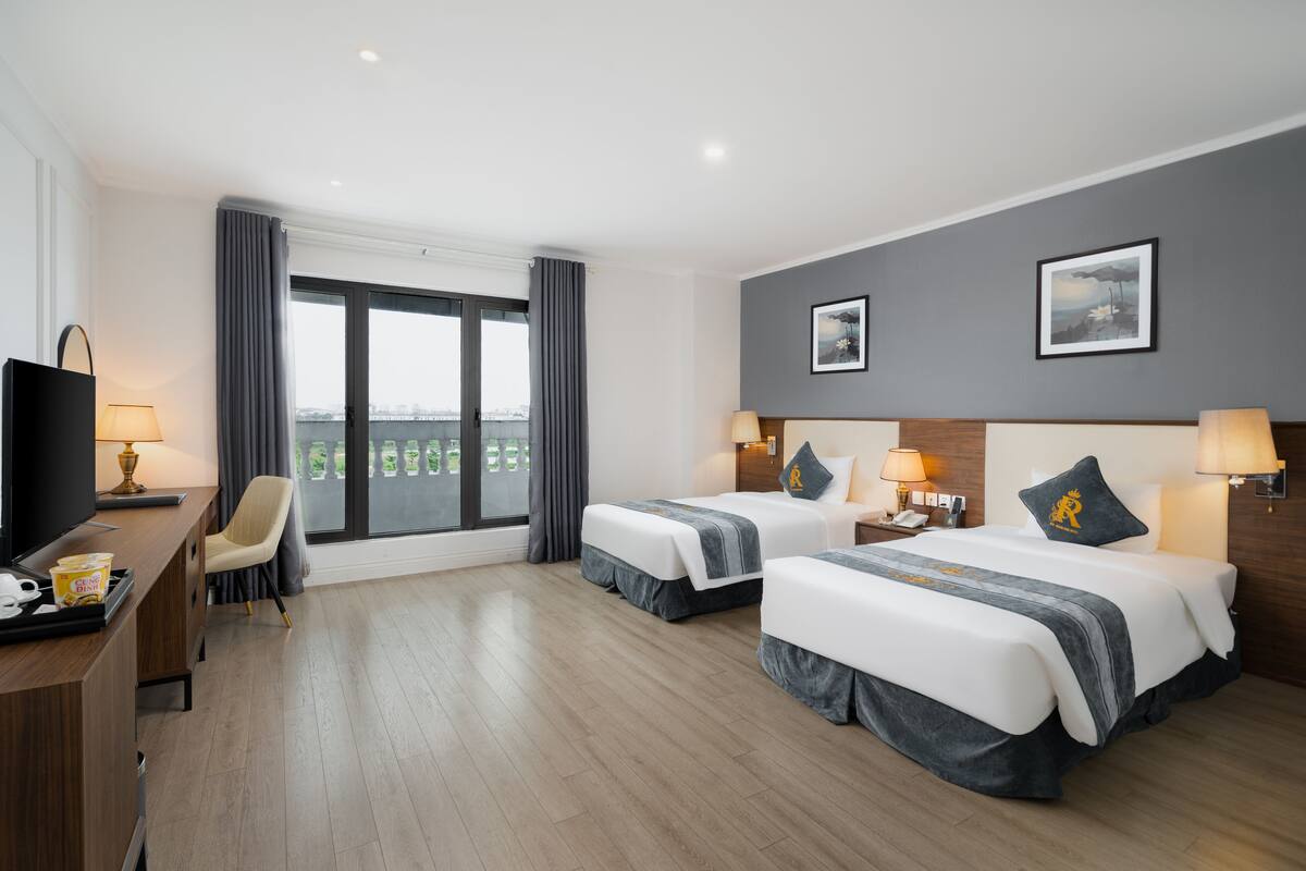 Een hotelkamer met twee bedden, een bureau, een stoel en een televisie.