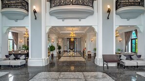 Een statige lobby met een gepolijste marmeren vloer, elegante kroonluchters en een centraal decoratief gedeelte.