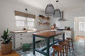 A modern kitchen with white cabinetry, a wooden island, and hanging pendant lights. - #18 Dog-Friendly 3BR Ocean-Block Cottage with Private Screened Porch in Rehoboth (Rehoboth Beach)